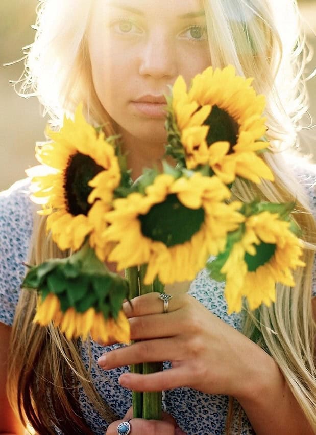 photo of young woman holding sunflowers